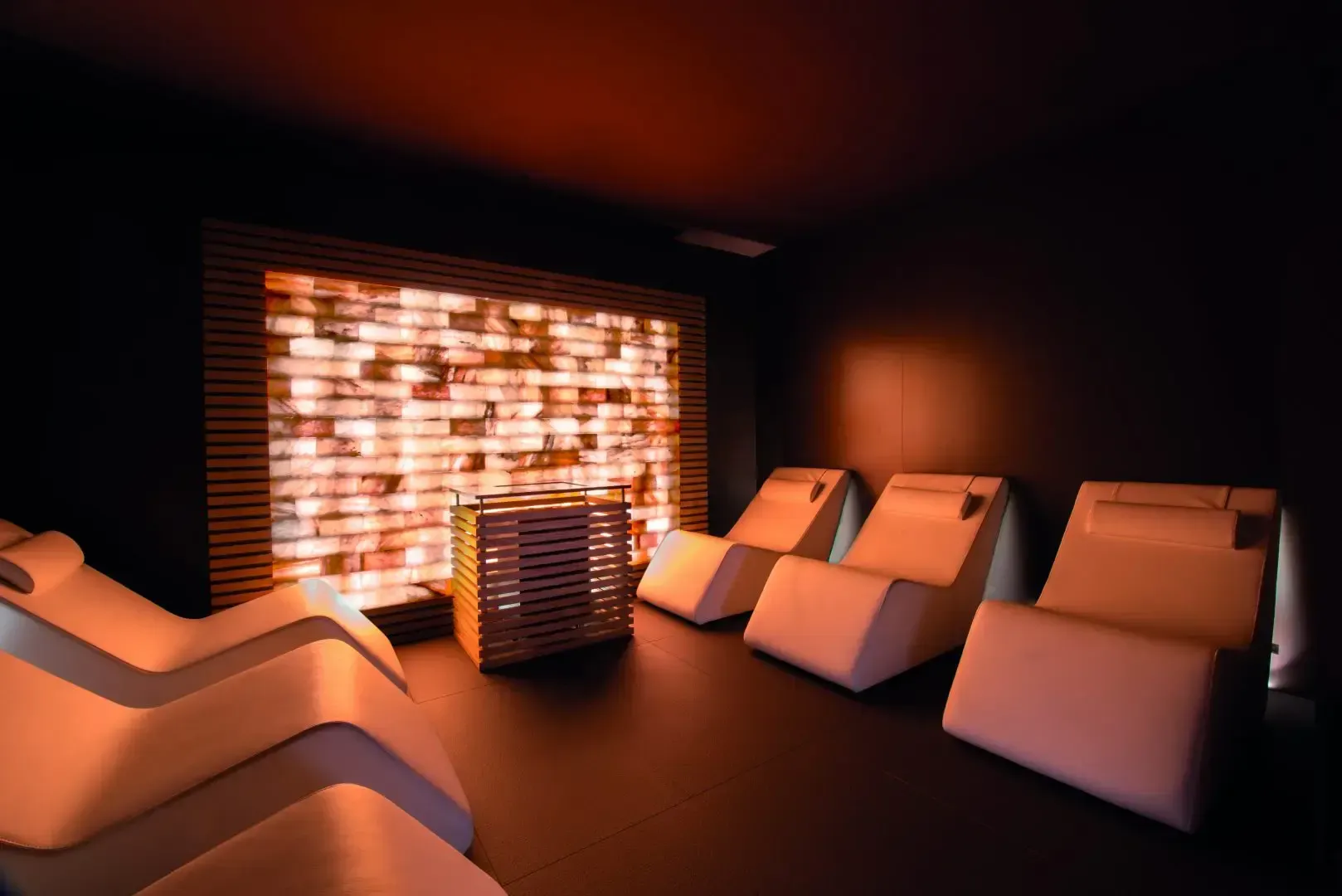 Sala relax con parete di sale illuminata, sedie a sdraio e luci soffuse.