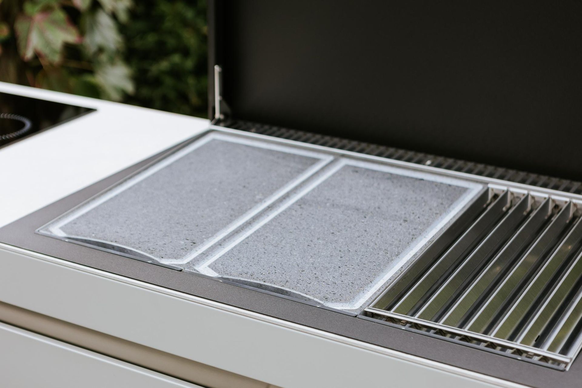 Barbecue da esterno con due superfici di cottura e griglie metalliche, coperchio aperto.