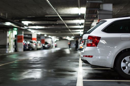 White car parked in a wet parking garage with other vehicles.