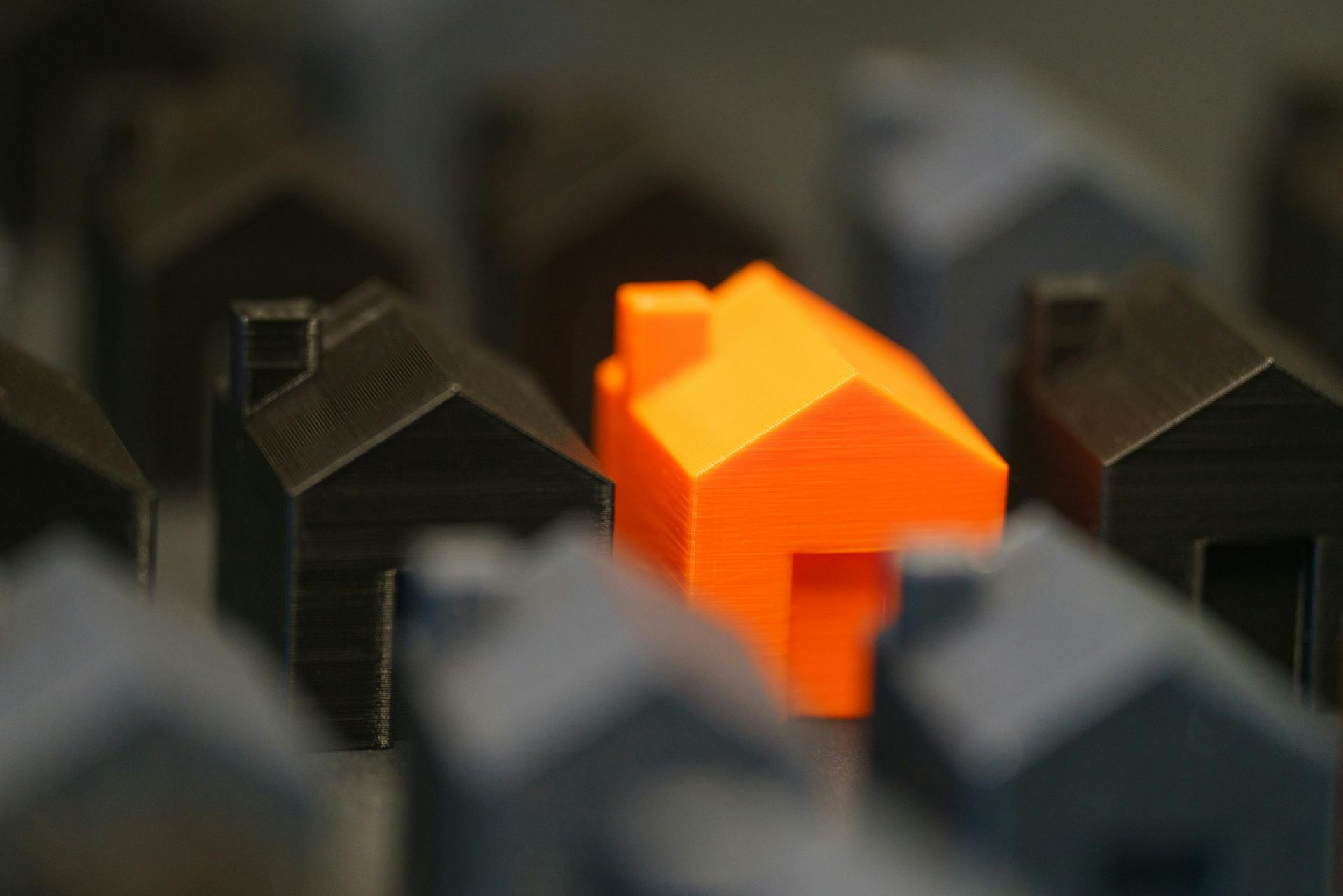 Orange house model among dark house models
