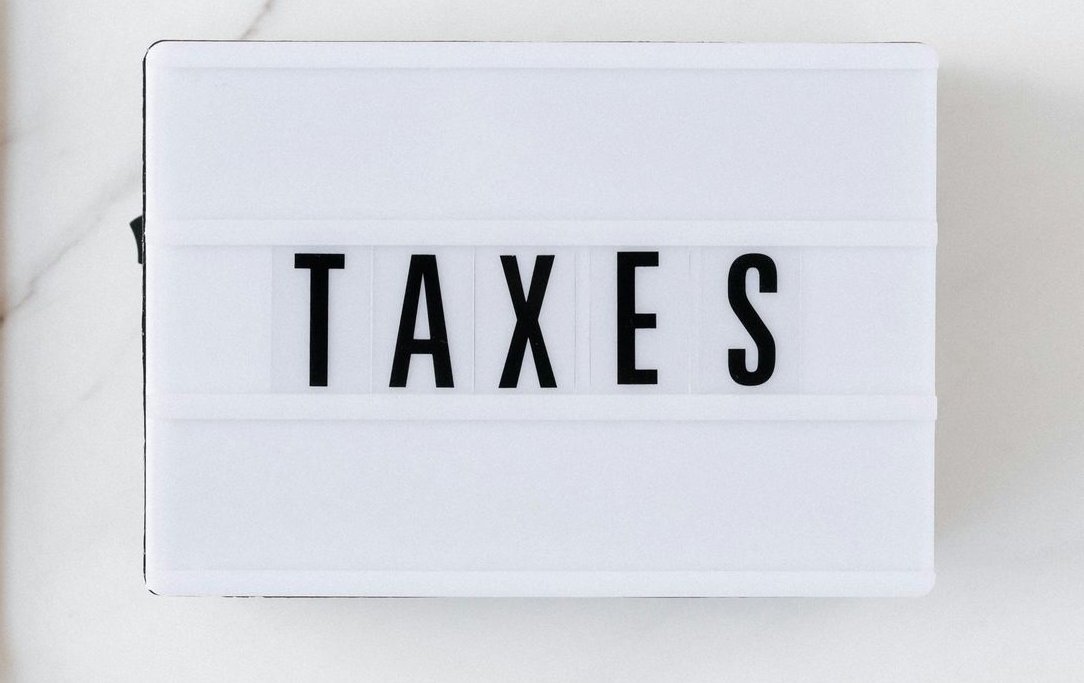 White sign with bold black text reading “TAXES”