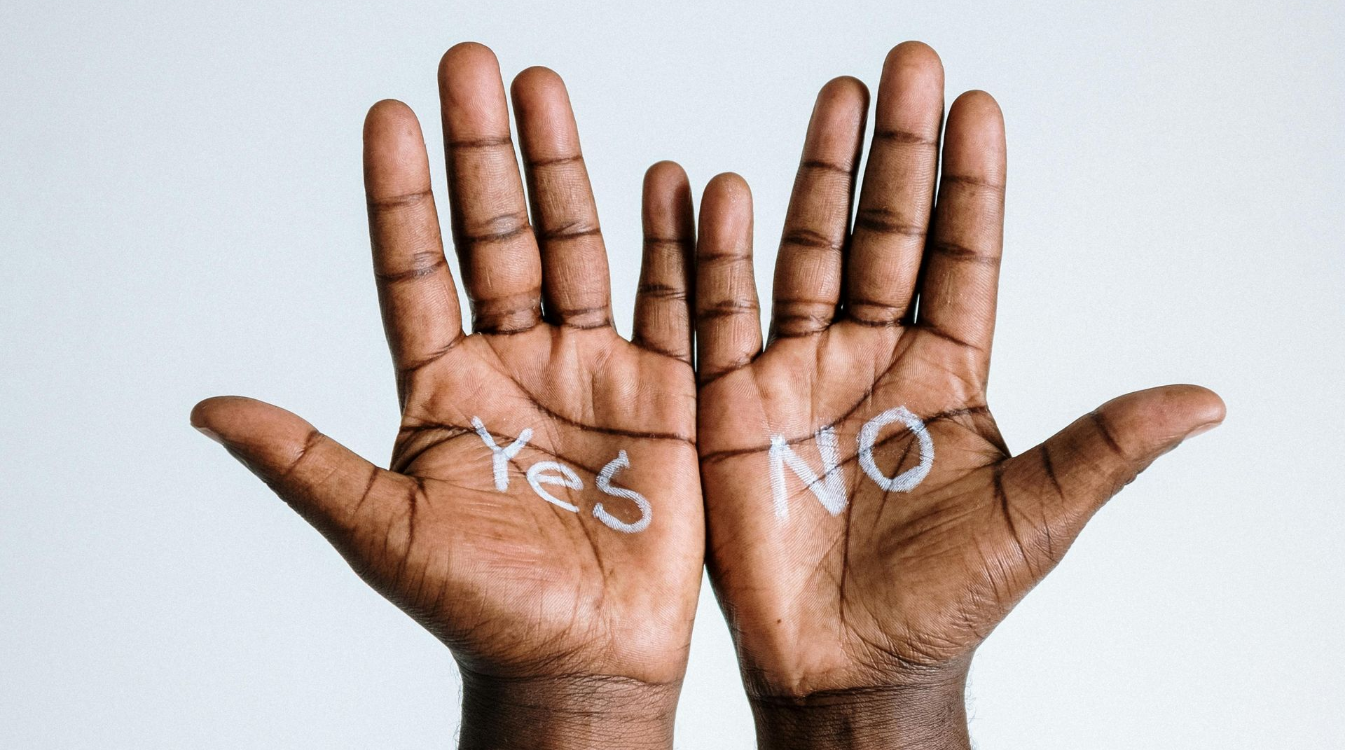Two open hands showing “Yes” and “No” written in white on the palms