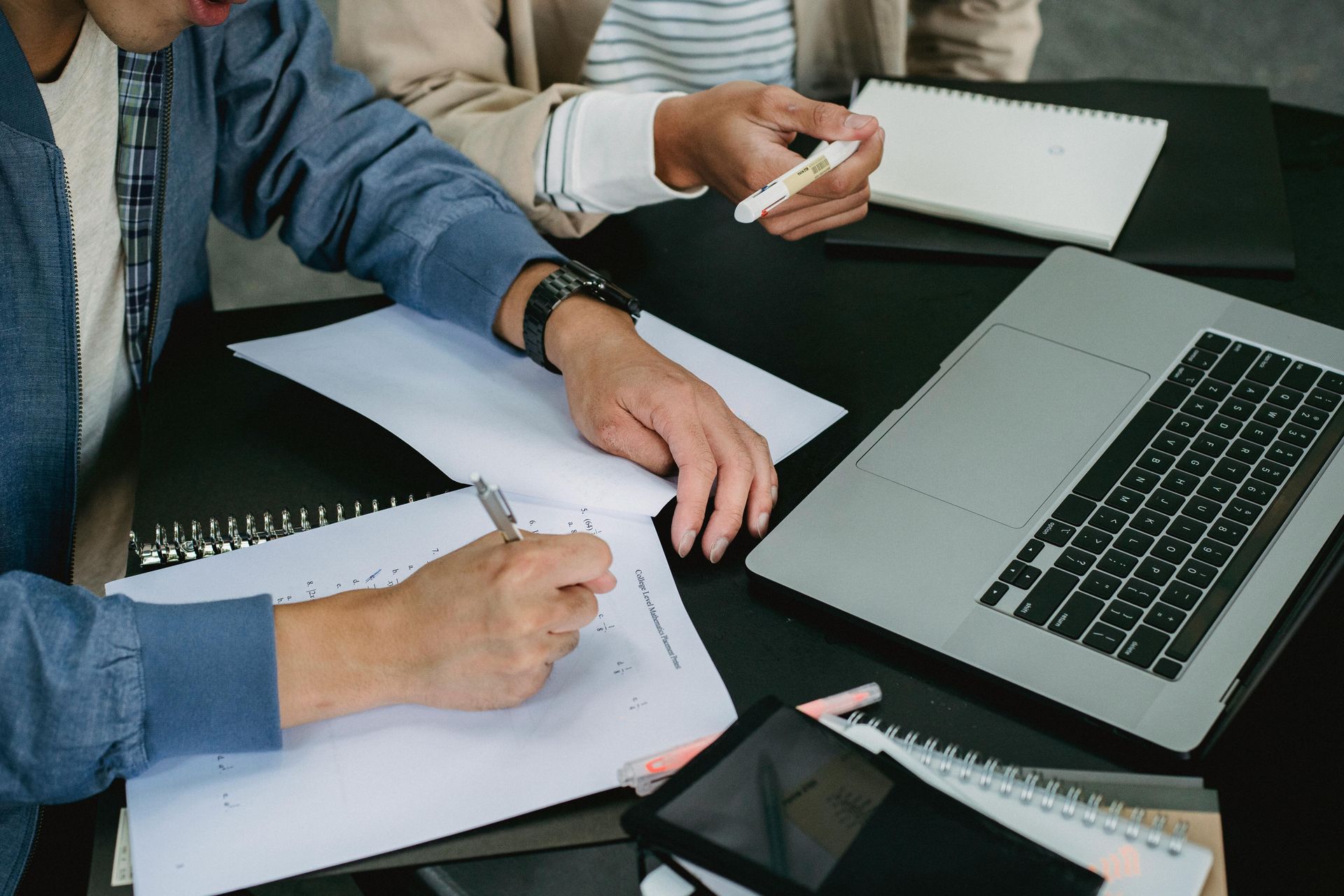 People reviewing documents beside a laptop at a table