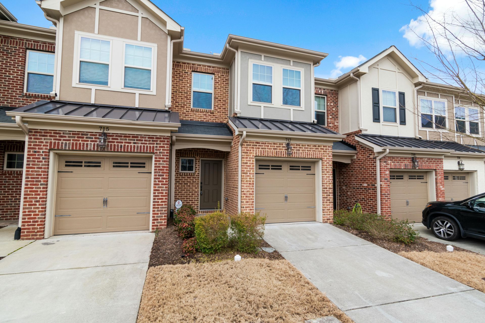 Row of beige townhouse garages with driveways and a car parked on the right