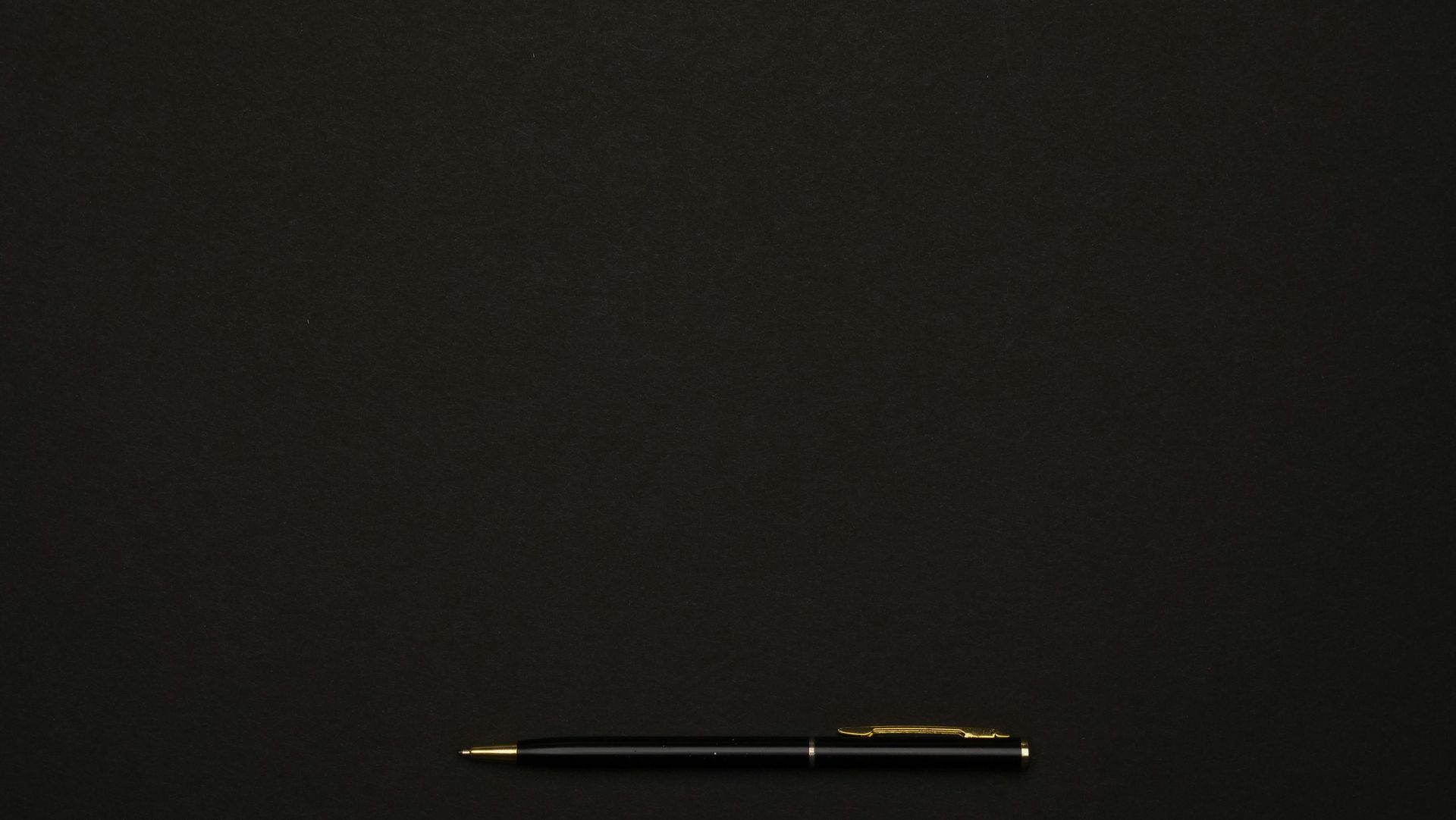 A black pen lying horizontally on a dark surface.