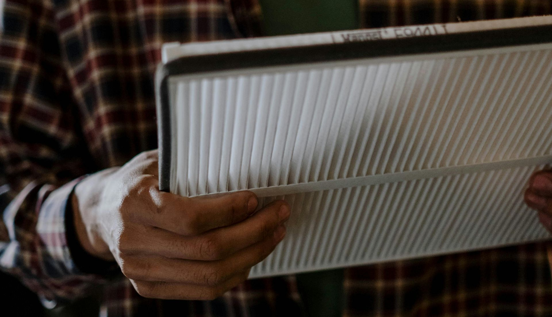Hands holding a white ribbed panel in a plaid shirt sleeve.