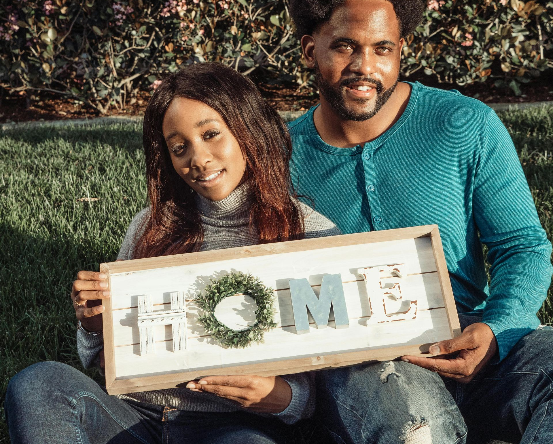Couple holding a home sign after buying their new house
