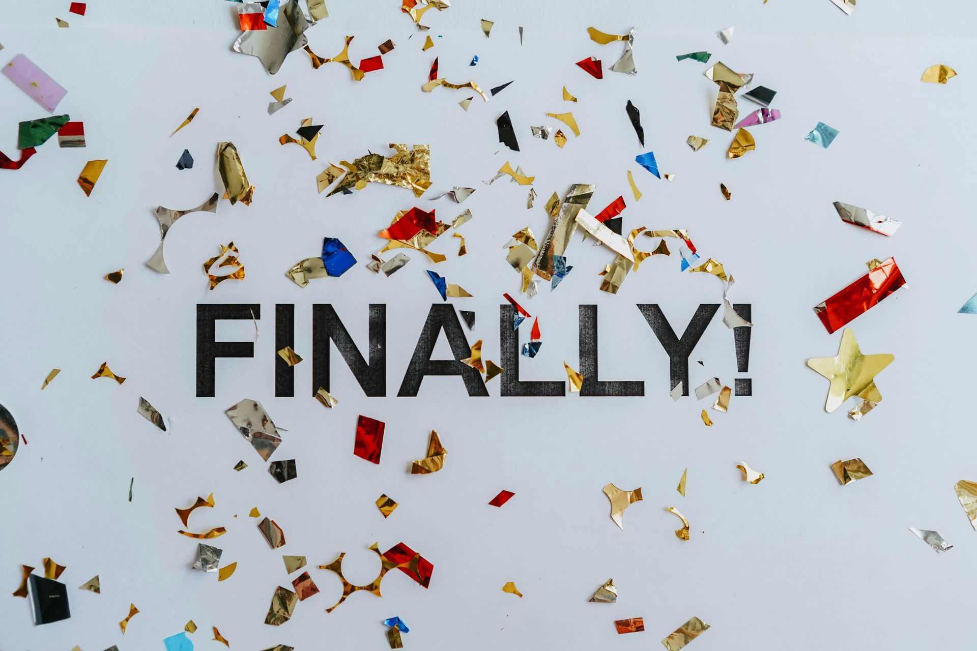 “FINALLY” text with colorful confetti scattered around on a light background