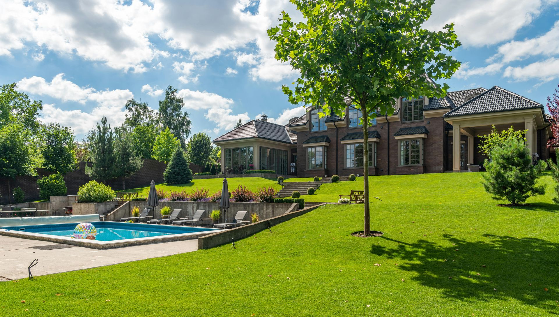 Luxurious house with landscaped lawn and swimming pool on a sunny day