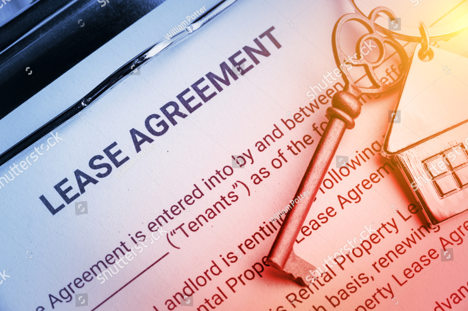 Lease agreement document beside car keys on a desk, highlighted in warm orange light.