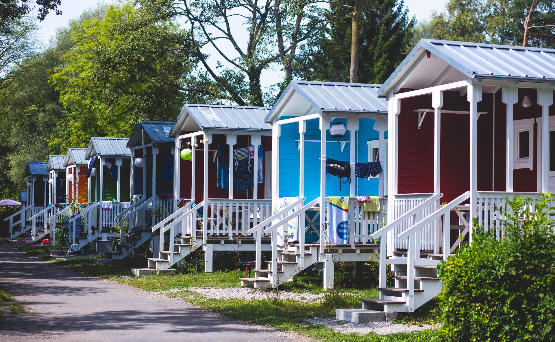 Colorful row of small cabins with white porches along a tree-lined path