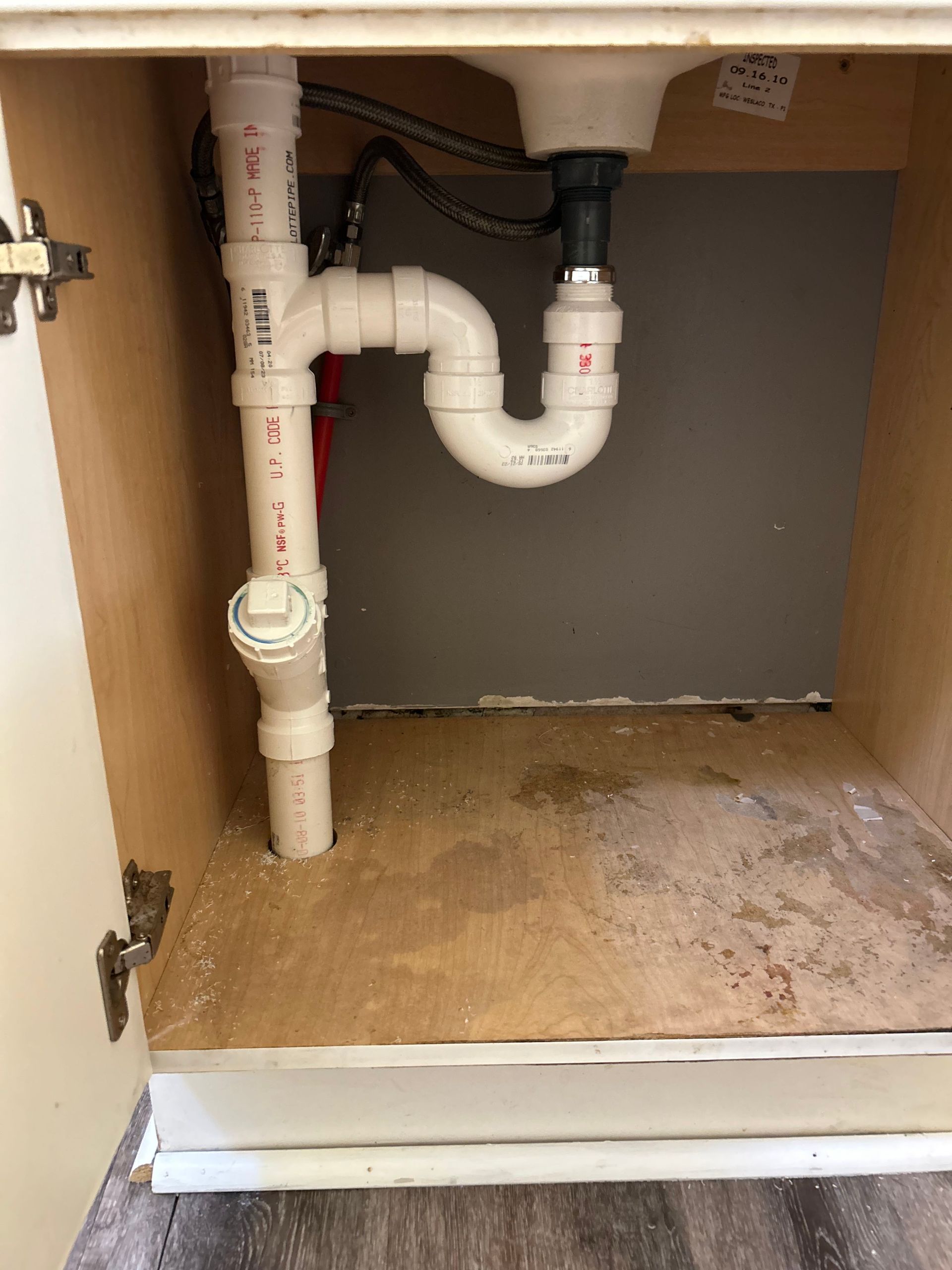 A sink with a plumbing pipe underneath it in a cabinet.
