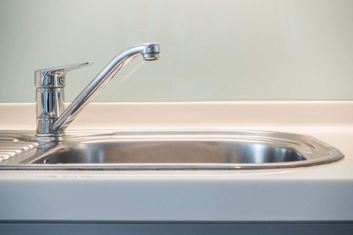 A close up of a stainless steel kitchen sink with a faucet.