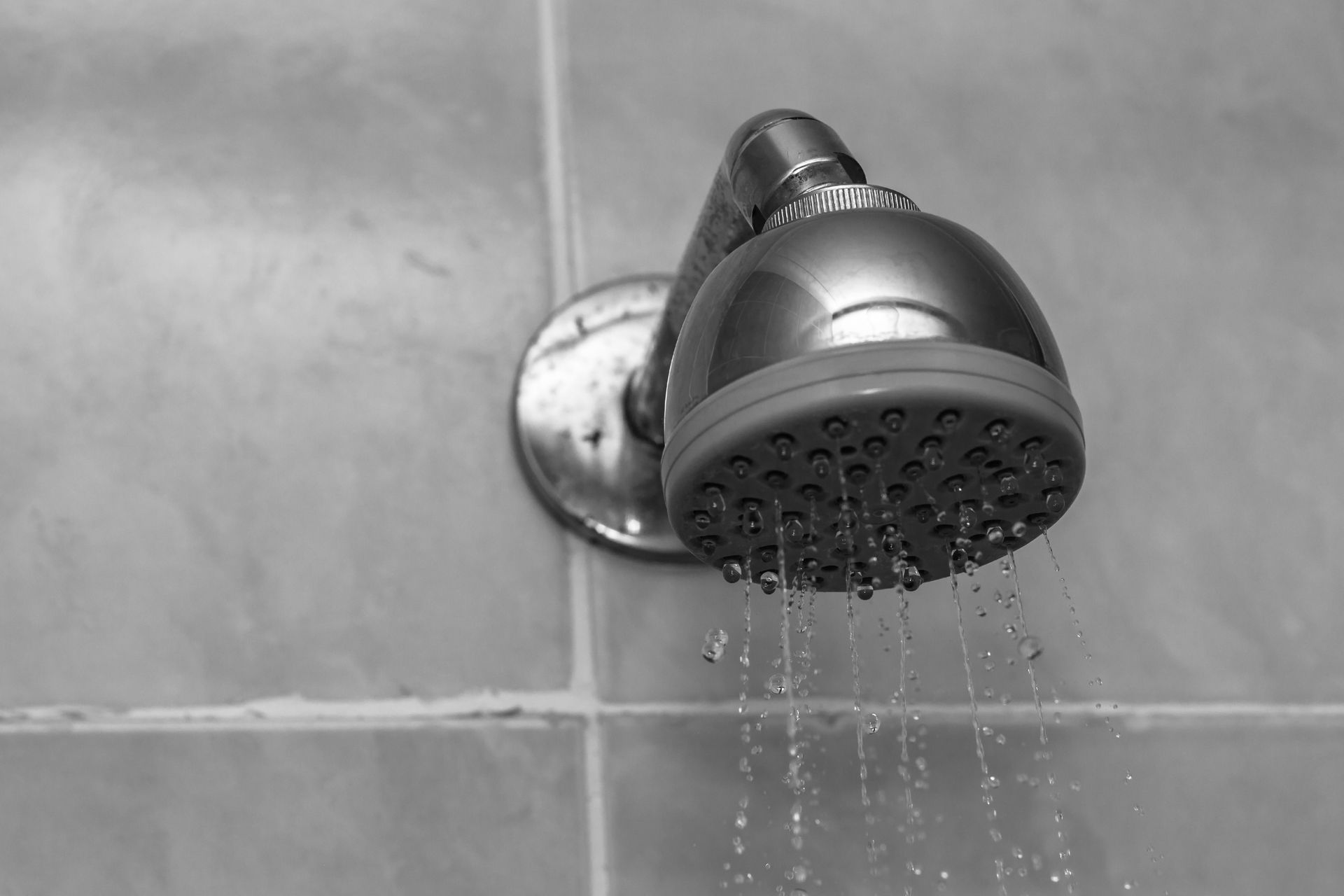 A black and white photo of a shower head with water coming out of it.