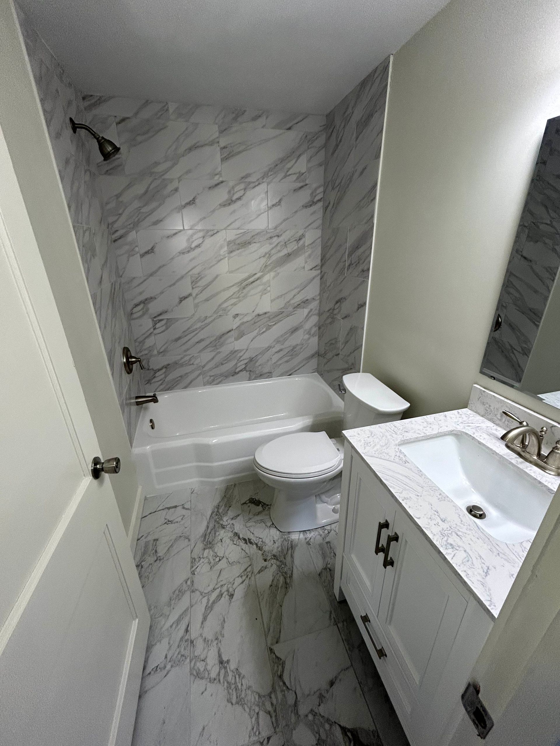 A bathroom with a tub , toilet , sink and mirror.