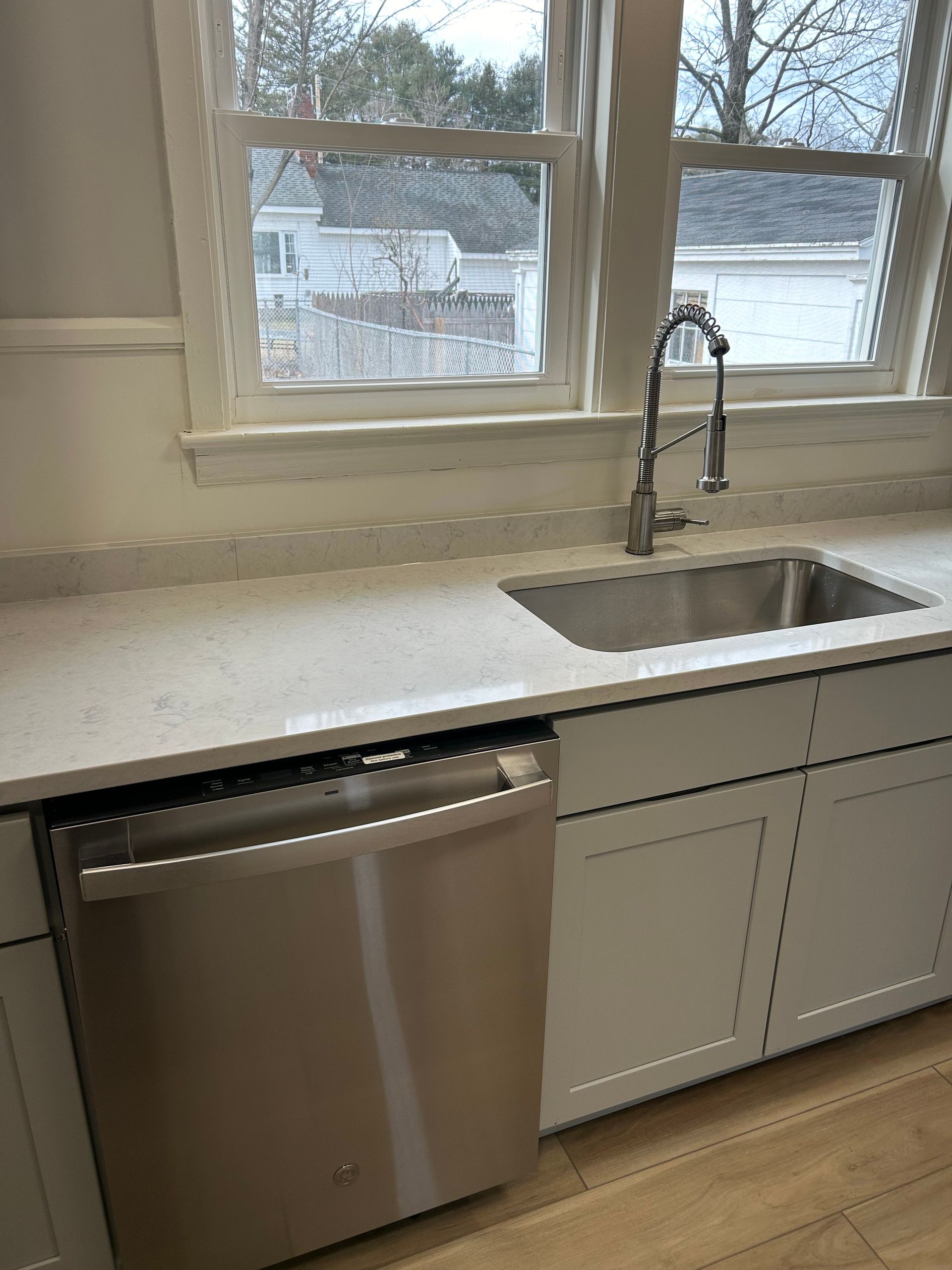 A kitchen with a sink , dishwasher , and window.