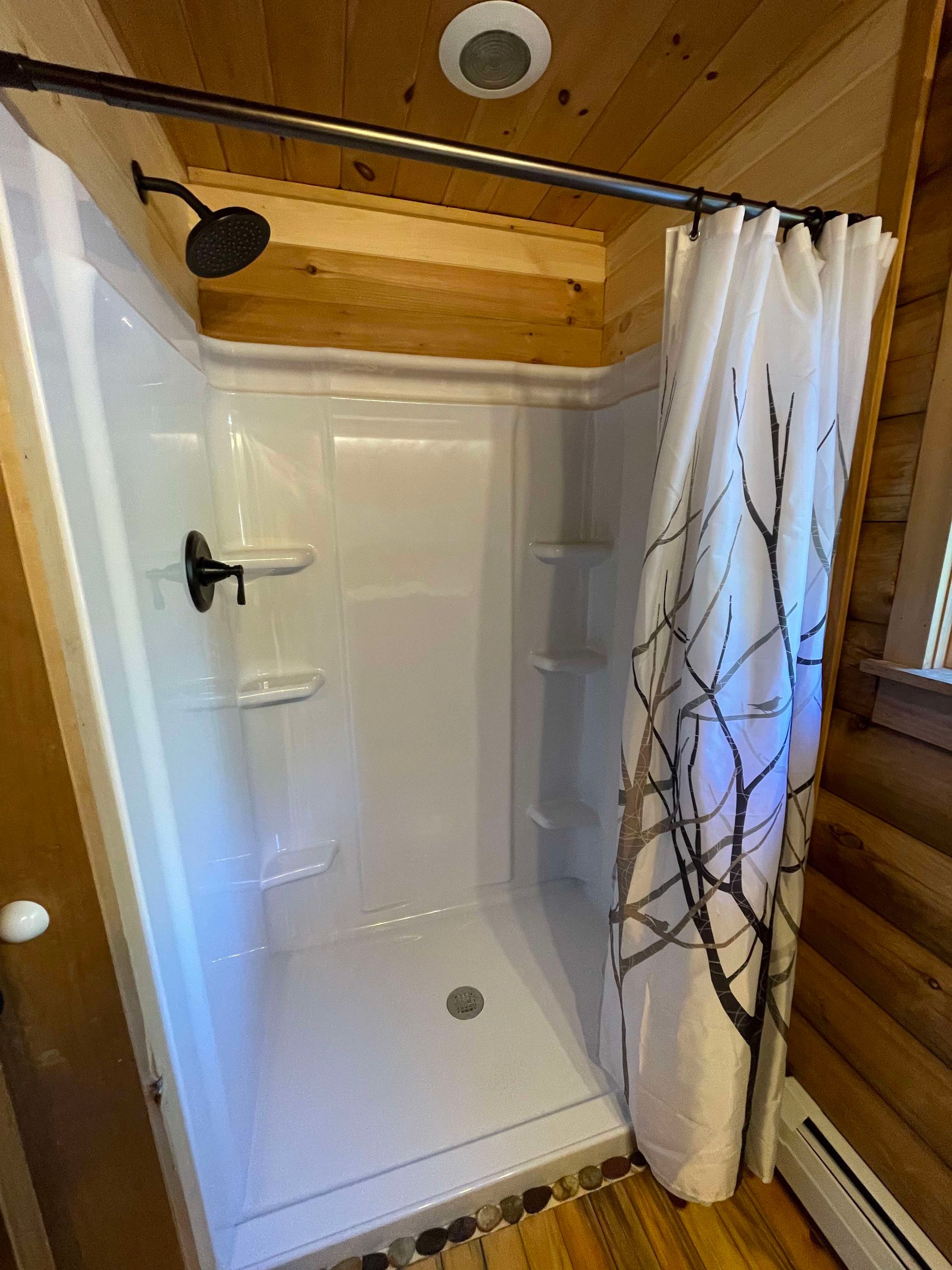 A shower in a log cabin with a shower curtain and a shower head.