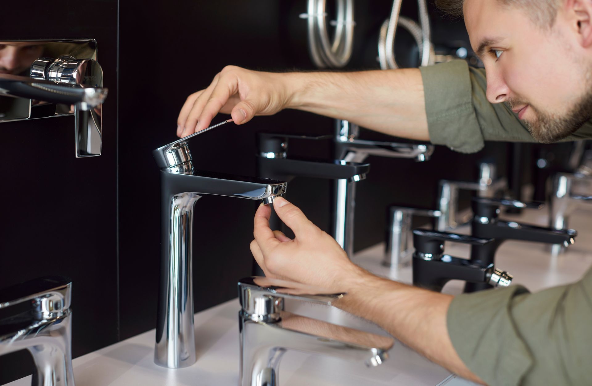 Person installing a chrome bathroom faucet at a sink counter