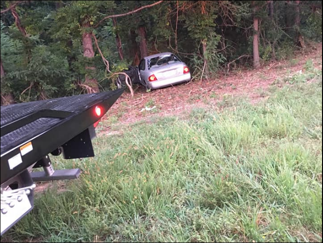 A tow truck is towing a car that has fallen off the road.