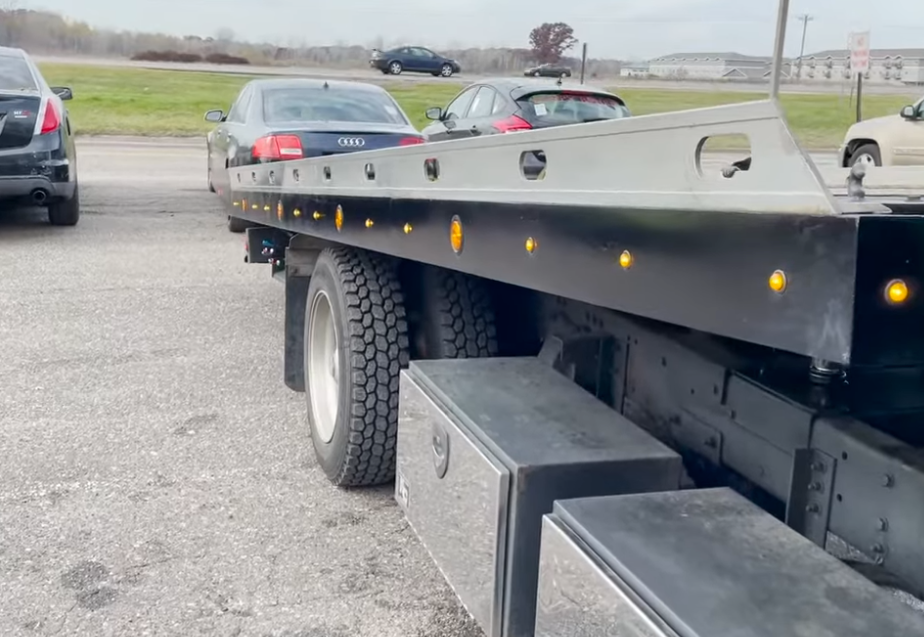 A tow truck is towing a car in a parking lot.