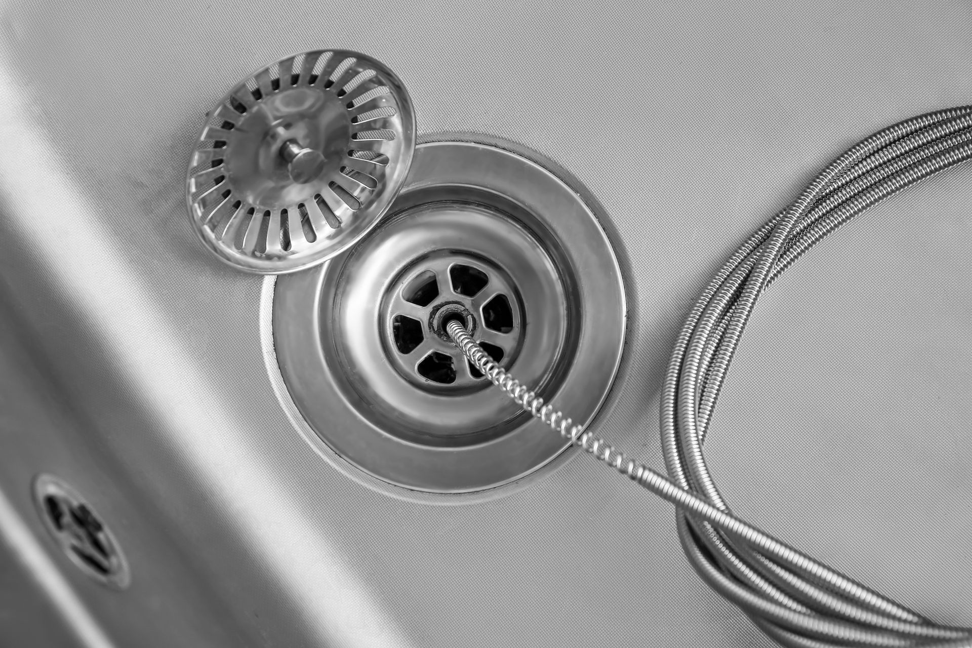 A black and white photo of a sink with a drain cleaner attached to it.