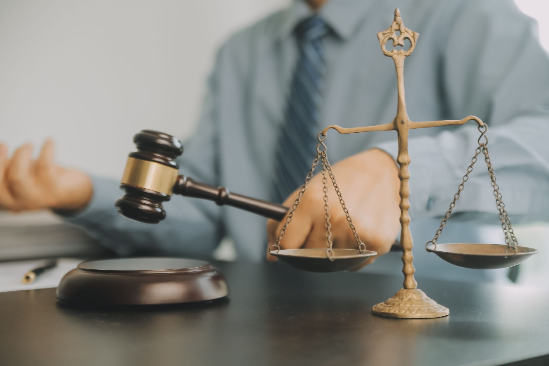 Judge’s gavel and scales on desk with a blurred lawyer in the background