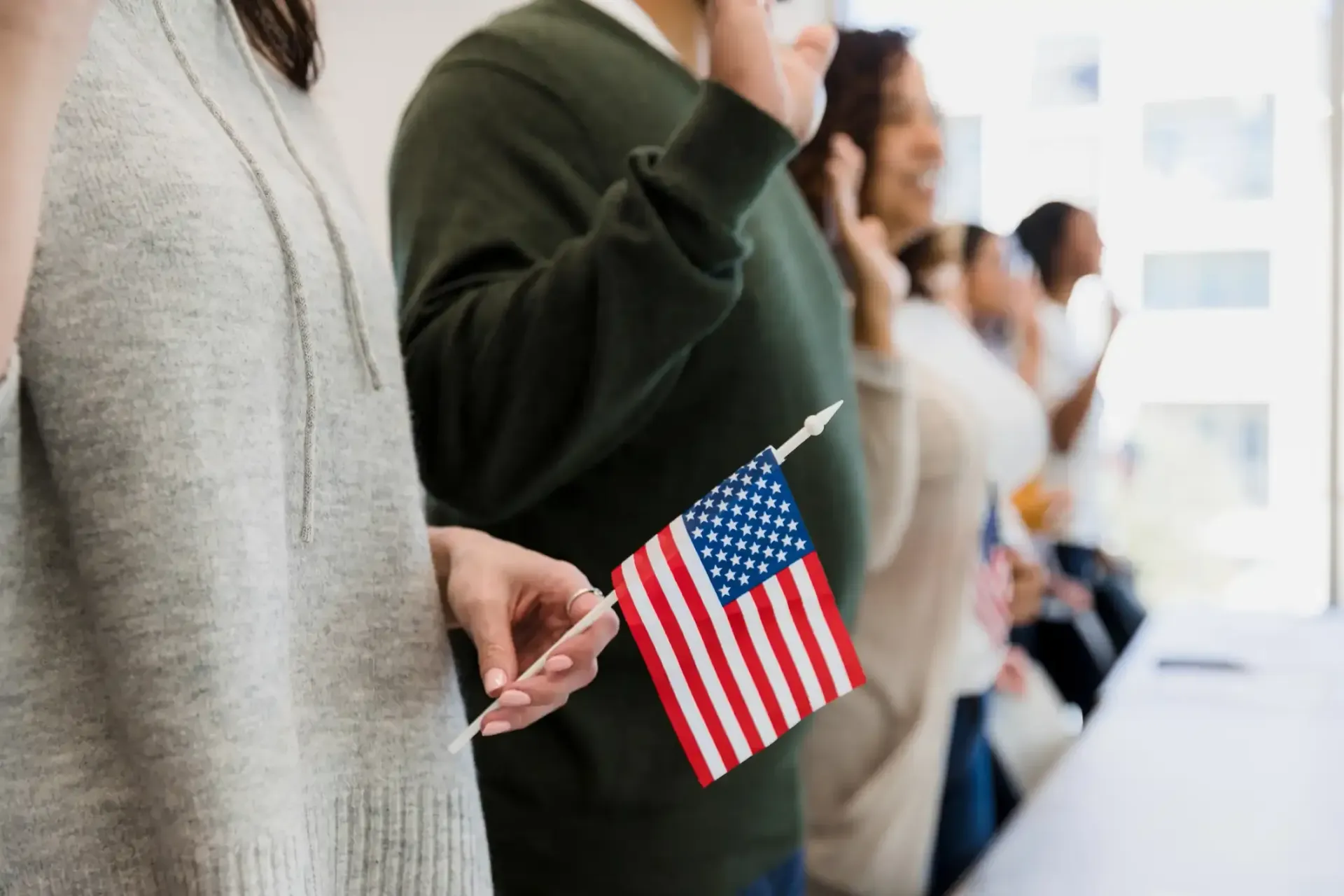 People holding small American flags in a bright indoor line
