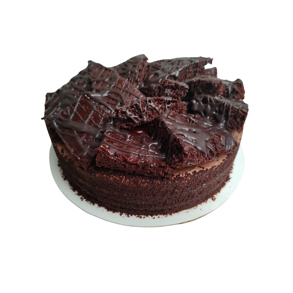 Pastel de chocolate con trozos de brownie encima, rociado con glaseado de chocolate, sobre un plato blanco de Azúcar y Cacao