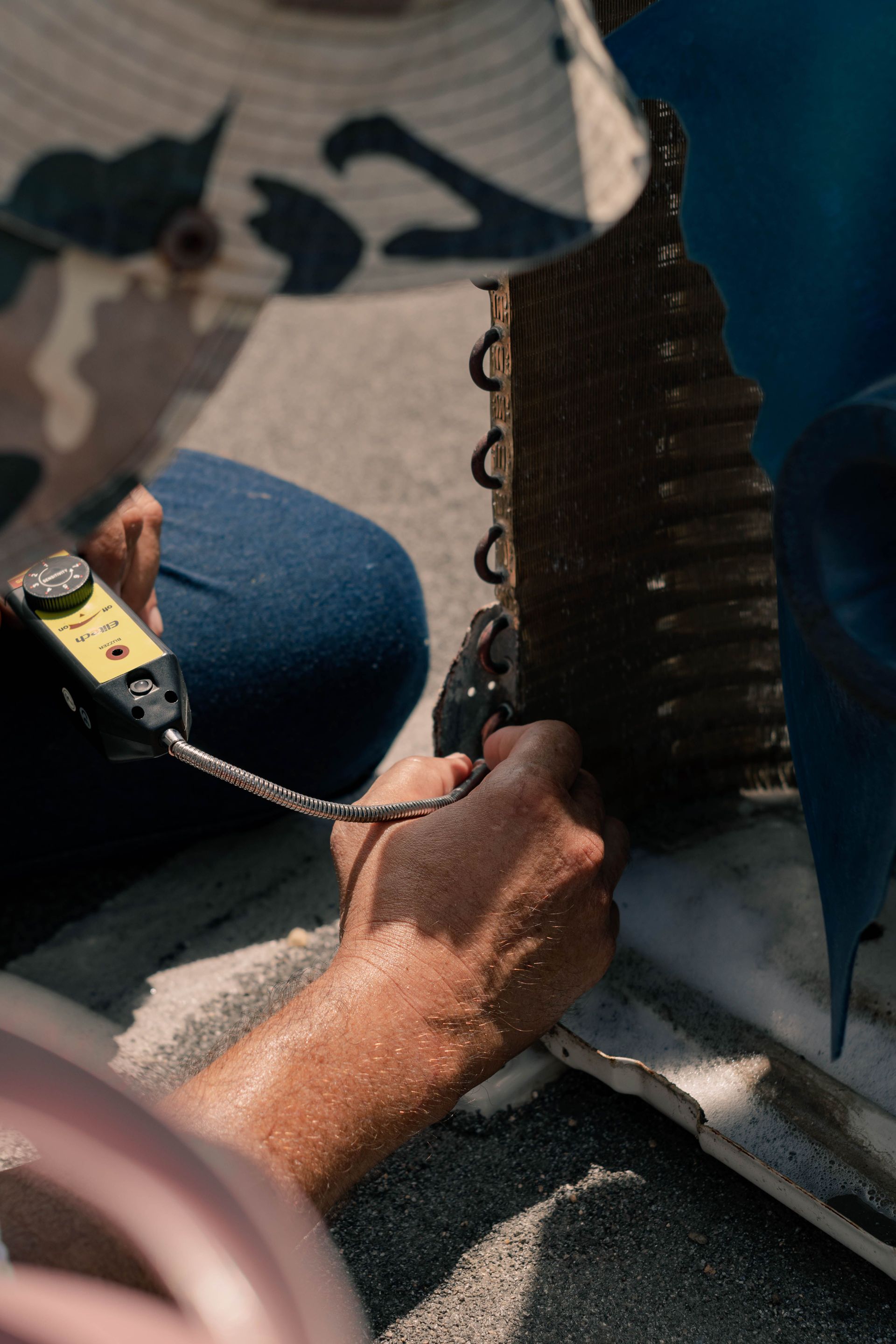 Person working on a damaged metal panel with tools, close-up view outdoors