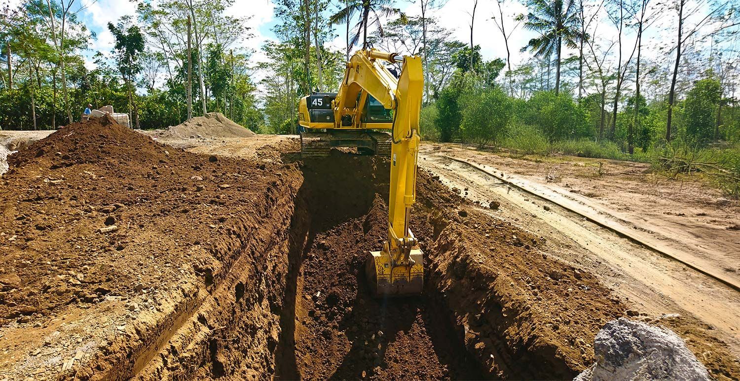 A yellow excavator is digging a hole in the dirt.