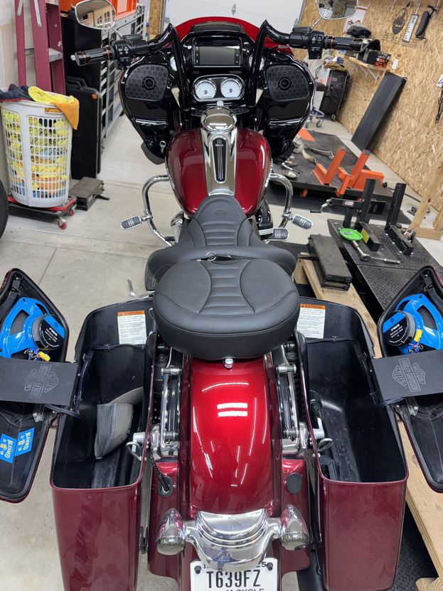 Red touring motorcycle in a garage, viewed from the rear with saddlebags and a seat