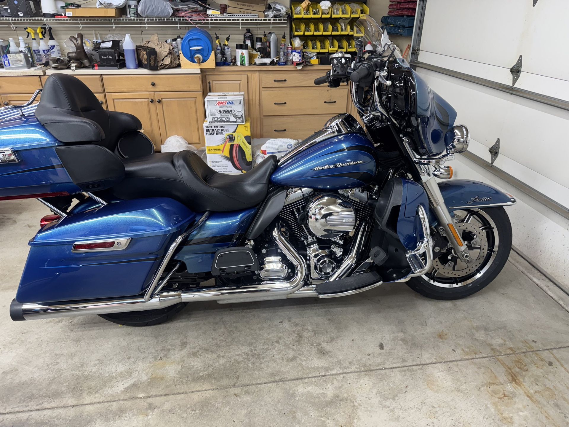 Blue touring motorcycle parked in a garage beside wooden cabinets and tools