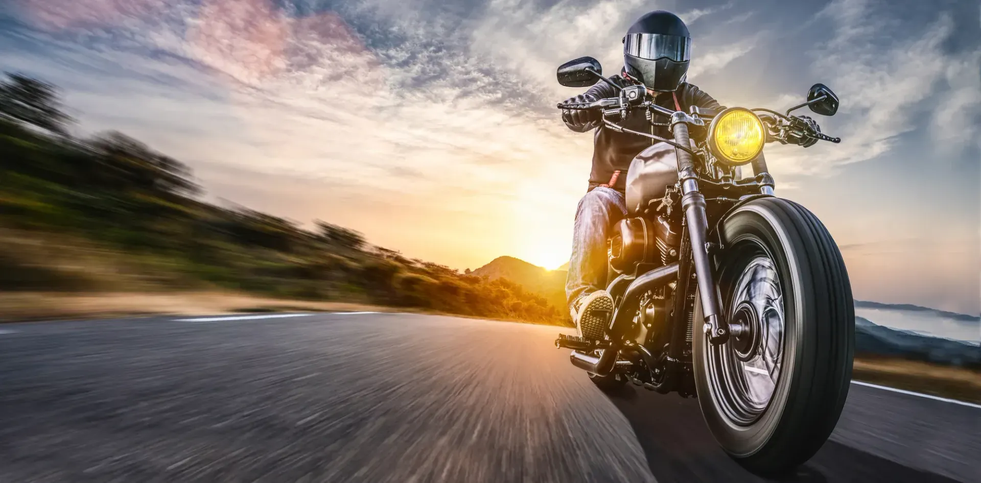 Motorcyclist riding on a winding country road, wearing a white helmet and jacket.