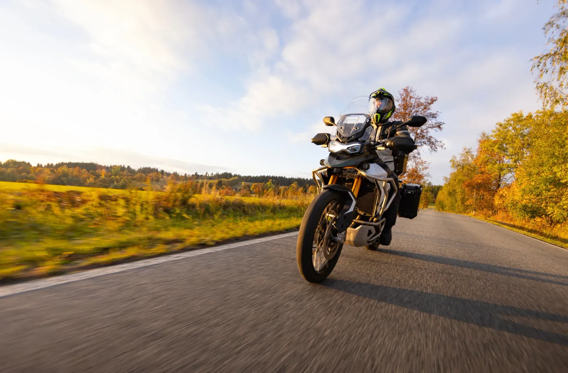 Motorcyclist riding on a winding country road with a helmet-mounted view of the handlebars and mirror
