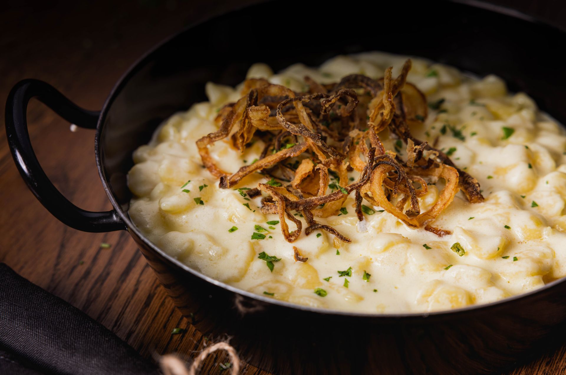 Eine Schüssel Makkaroni mit Käse und Röstzwiebeln auf einem Holztisch.