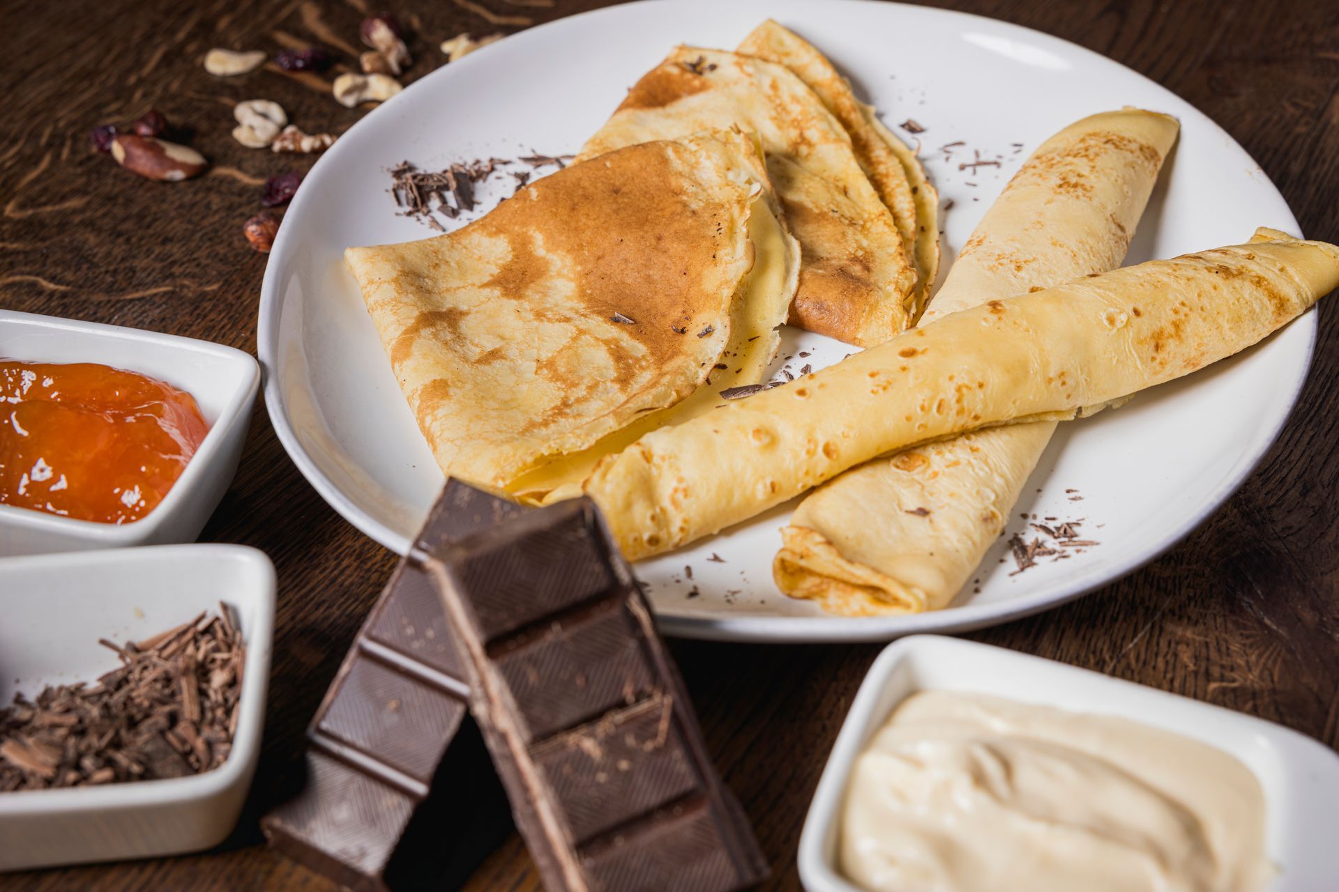 Ein weißer Teller, belegt mit Pfannkuchen, Schokolade und Soßen.