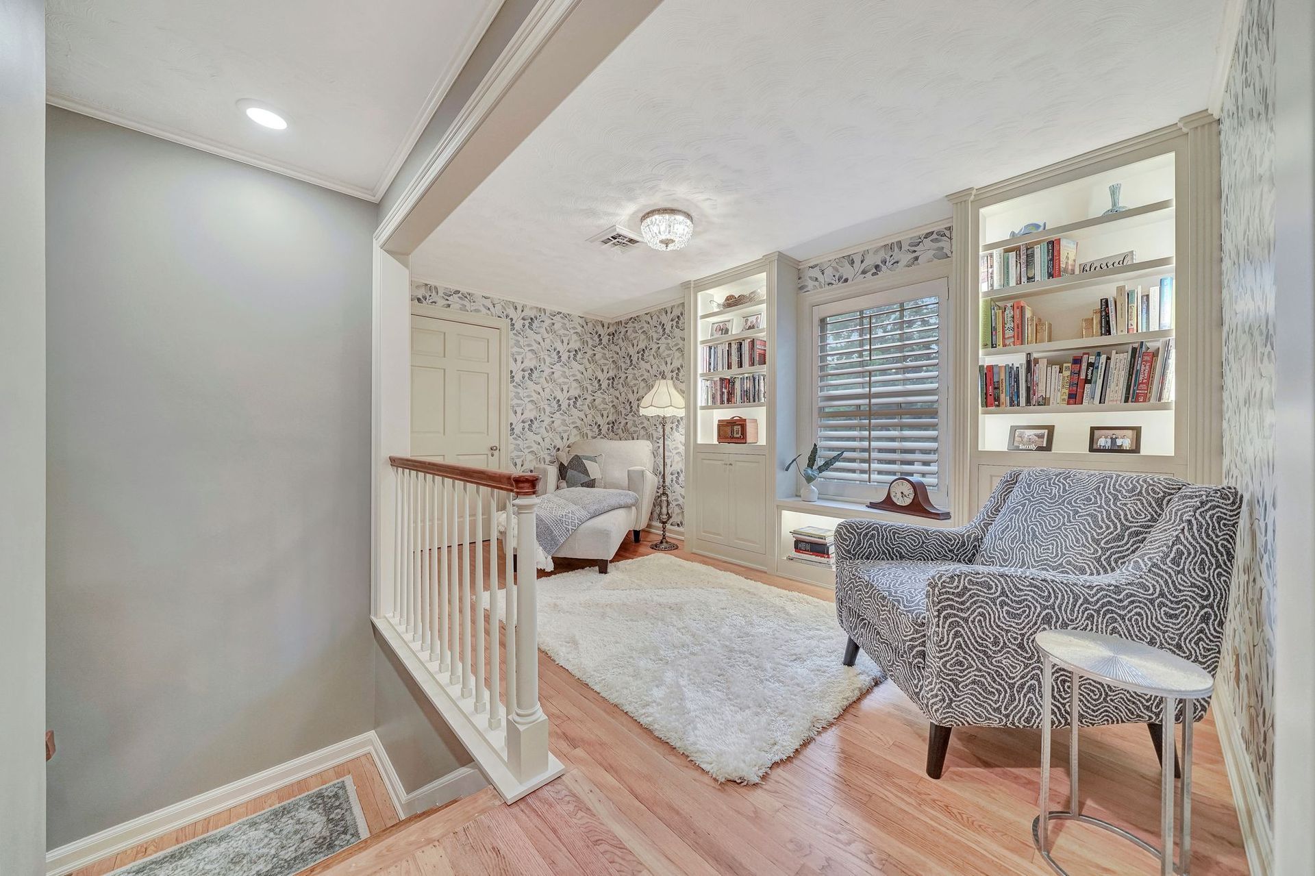 Cozy reading nook with built-in bookshelves, patterned chairs, and a fluffy white rug.