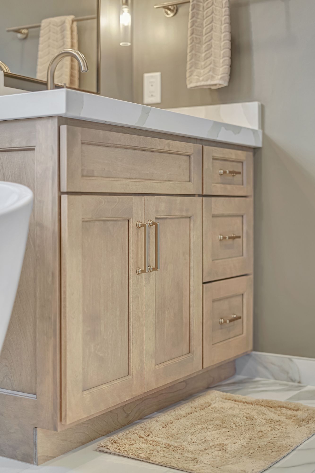 Light wood bathroom vanity with marble countertop, drawers, and cabinet doors.