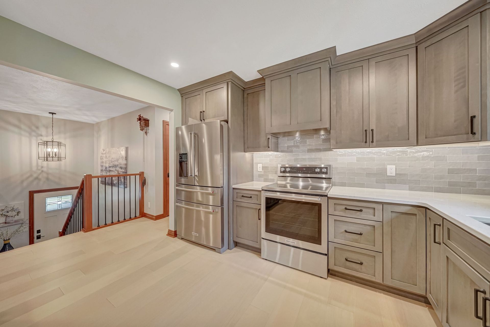 Kitchen with gray cabinets, stainless steel appliances, and light wood flooring.