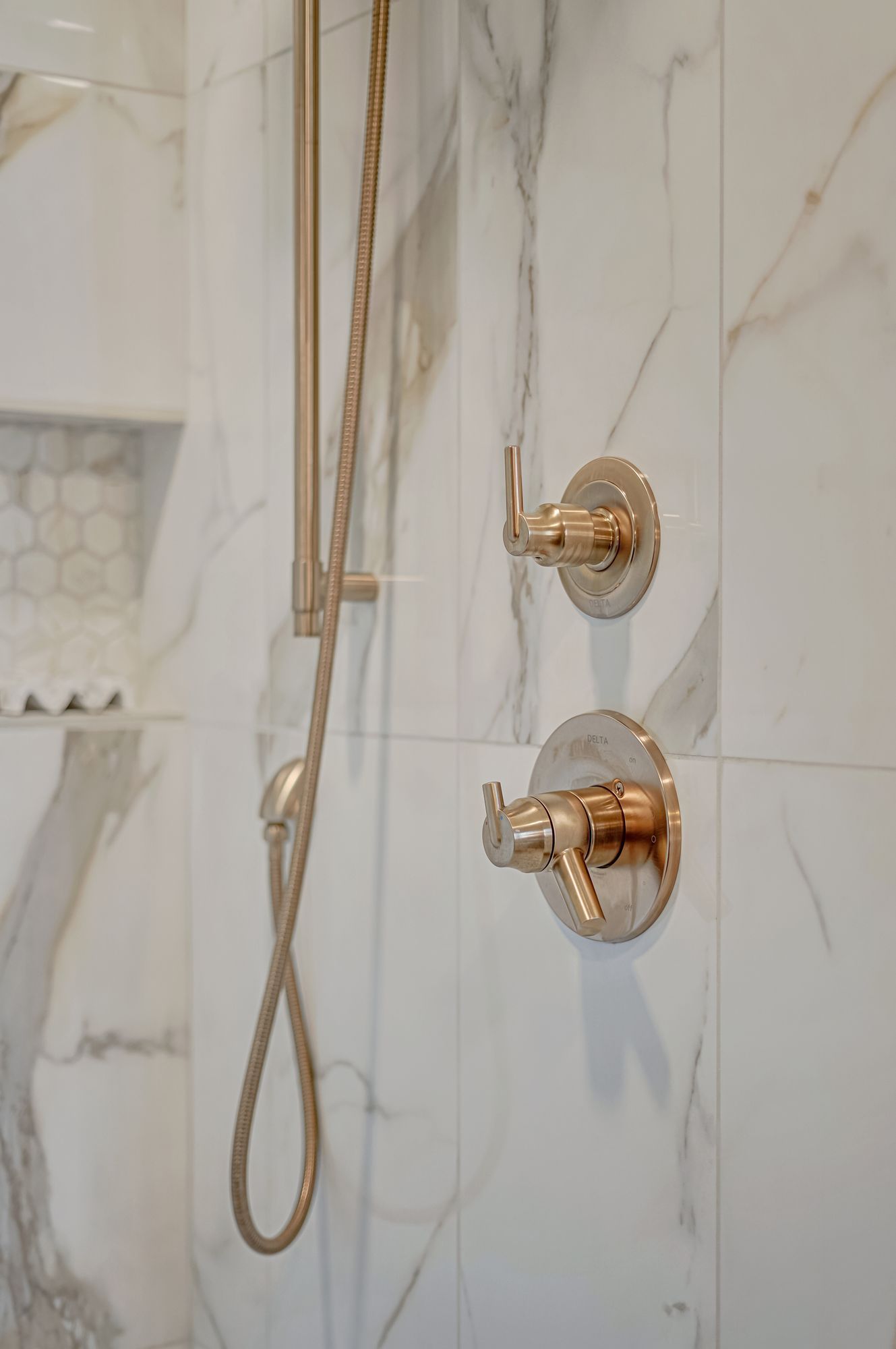 Gold shower fixtures against white marble tile.