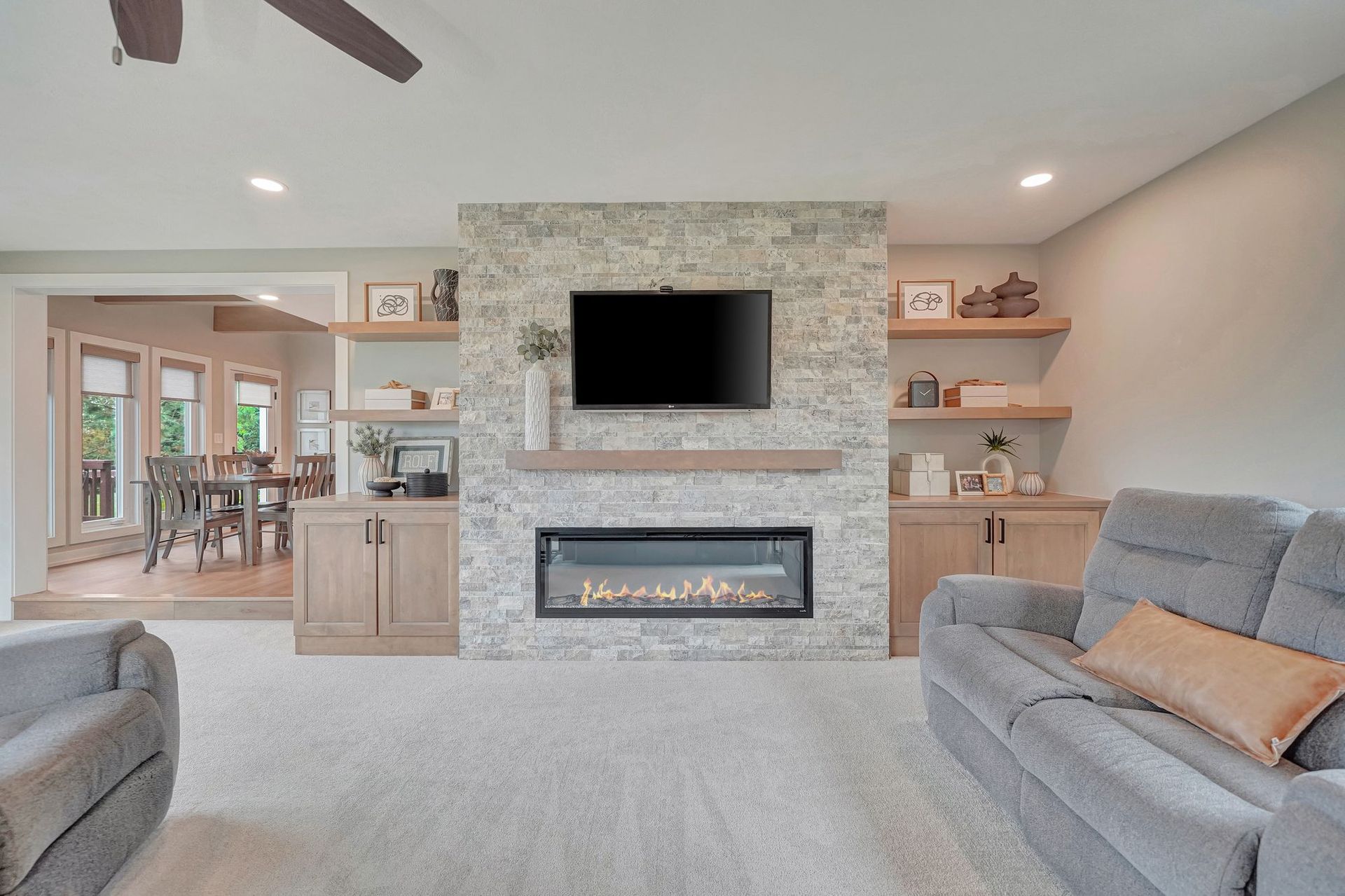 Living room with gray couch, fireplace, TV, and light wood built-ins.