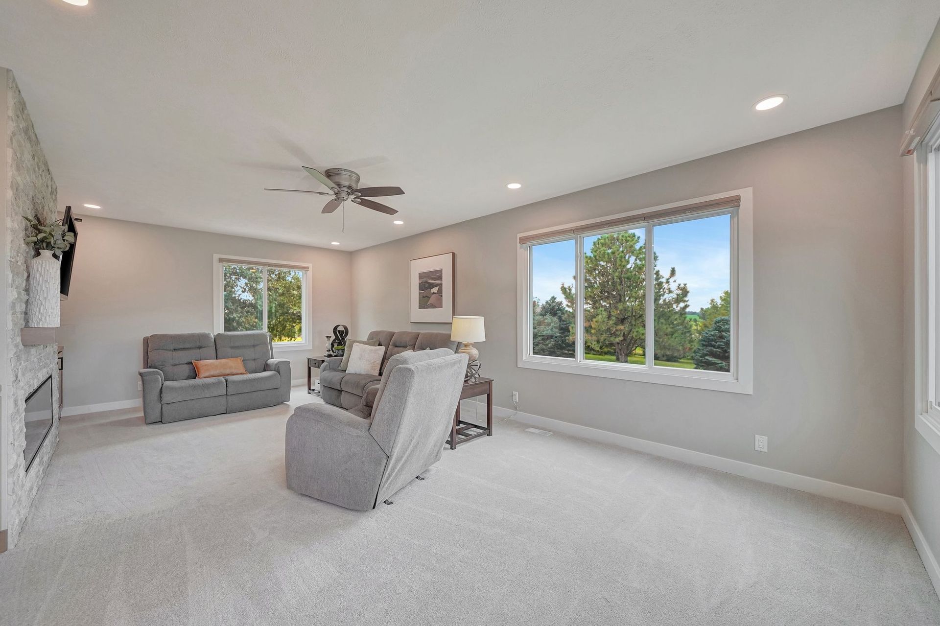 Spacious living room with gray furniture, large windows, and white walls and ceiling.