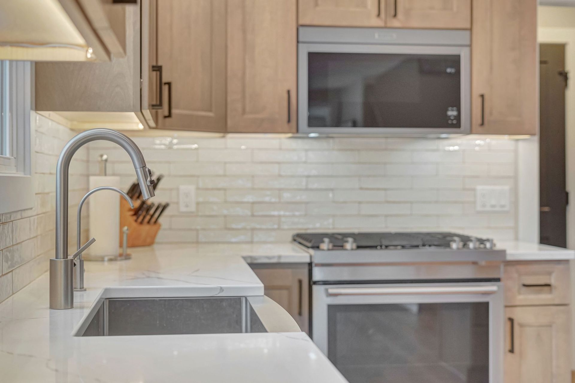 Kitchen with stainless steel appliances, light wood cabinets, white countertops and backsplash.