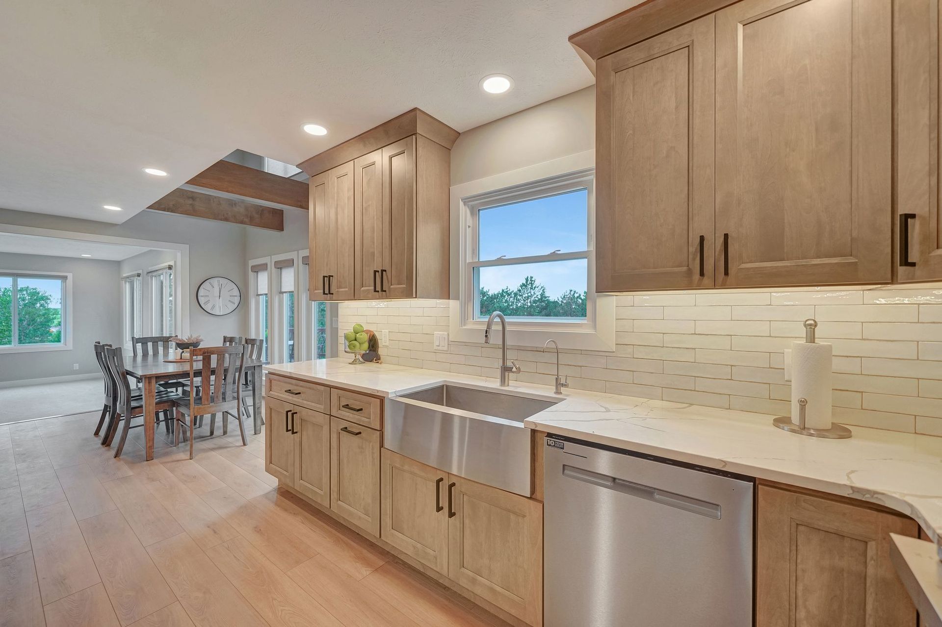 Light wood kitchen with stainless steel sink and appliances; dining area visible.
