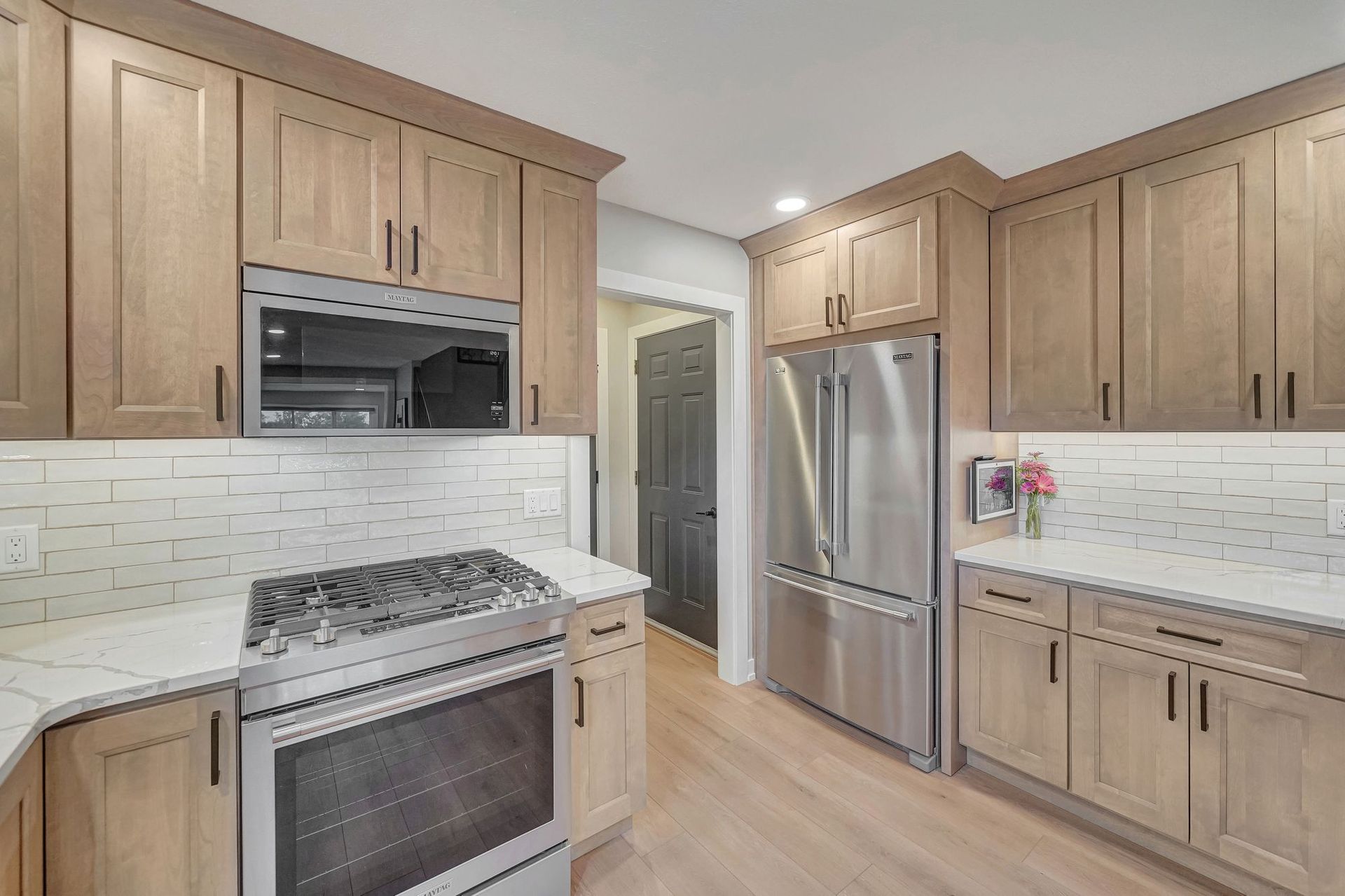 Kitchen with light wood cabinets, stainless steel appliances, and white countertops.