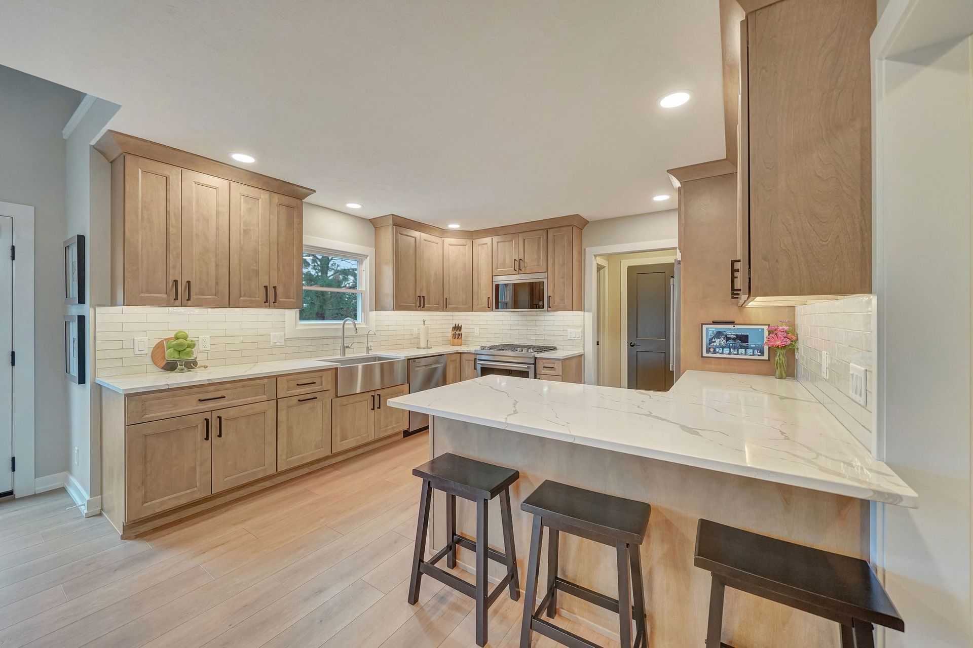 Kitchen with light wood cabinets, white countertops, and bar seating.
