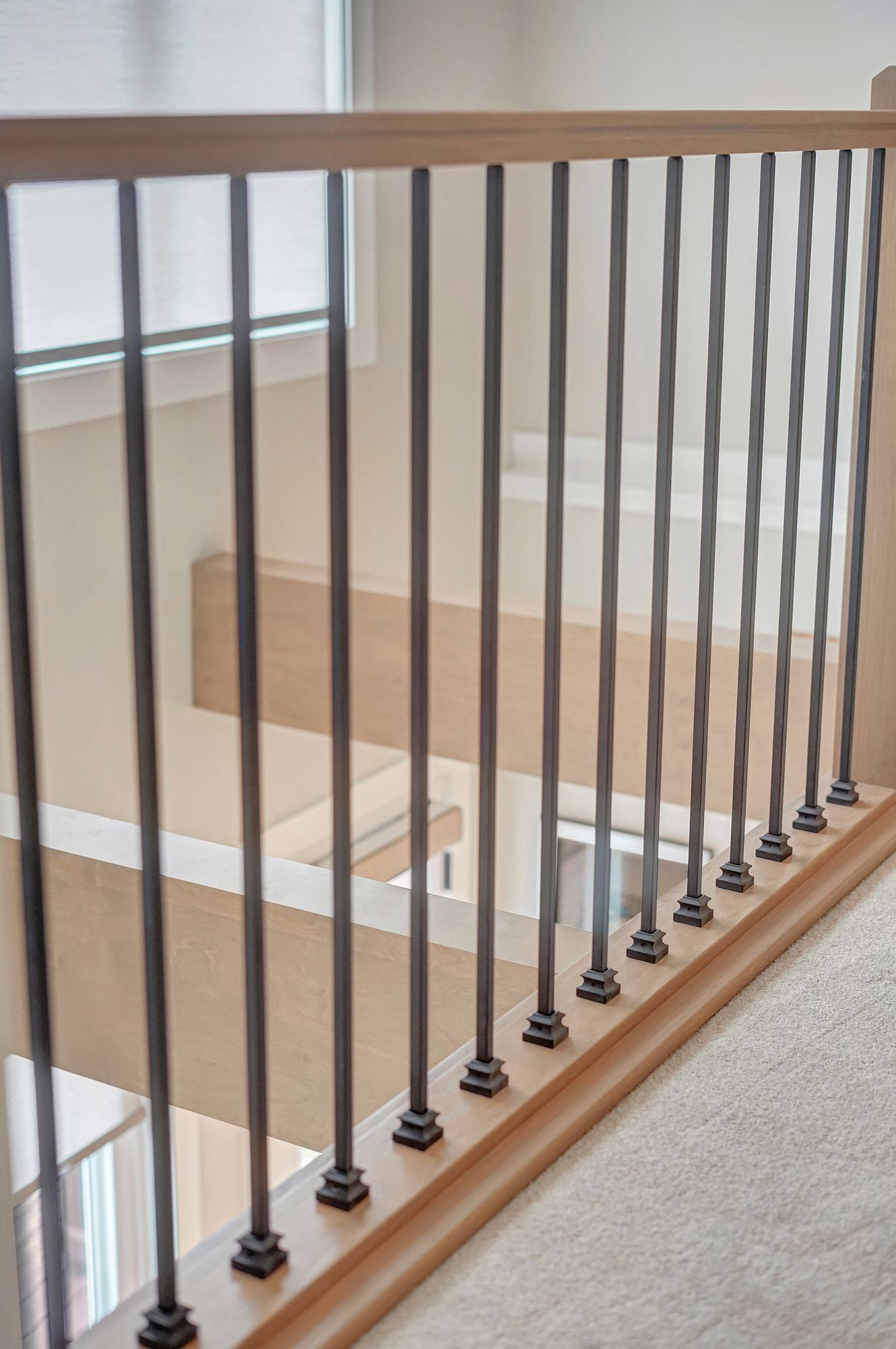 Wooden staircase railing with dark metal spindles.