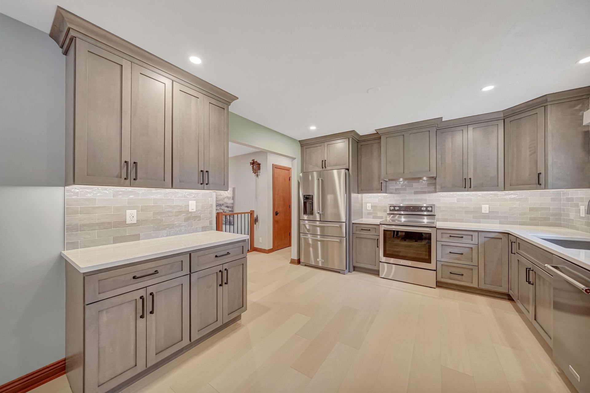 Gray kitchen cabinets and appliances in a modern kitchen with light wood floors.