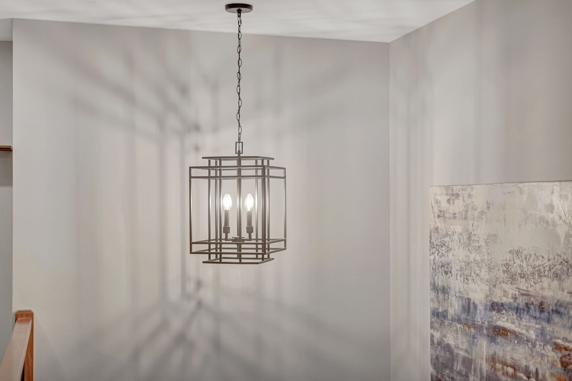 Lantern-style chandelier hanging from ceiling, casting shadows on the light gray walls.
