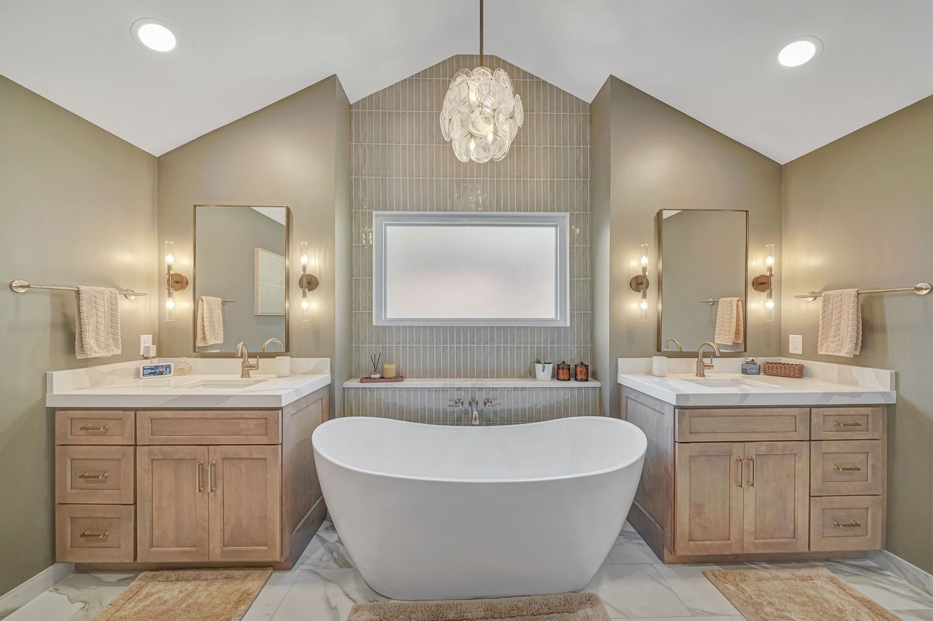 Bathroom with two vanities, a freestanding tub, and a decorative light fixture.